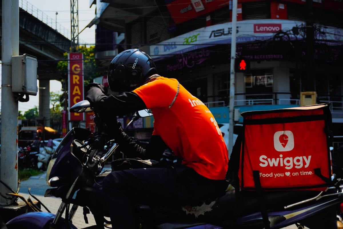 Indian delivery partner on a motorcycle with a Swiggy food delivery bag